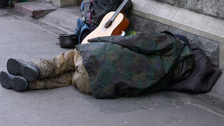 Homeless man on ground with guitar