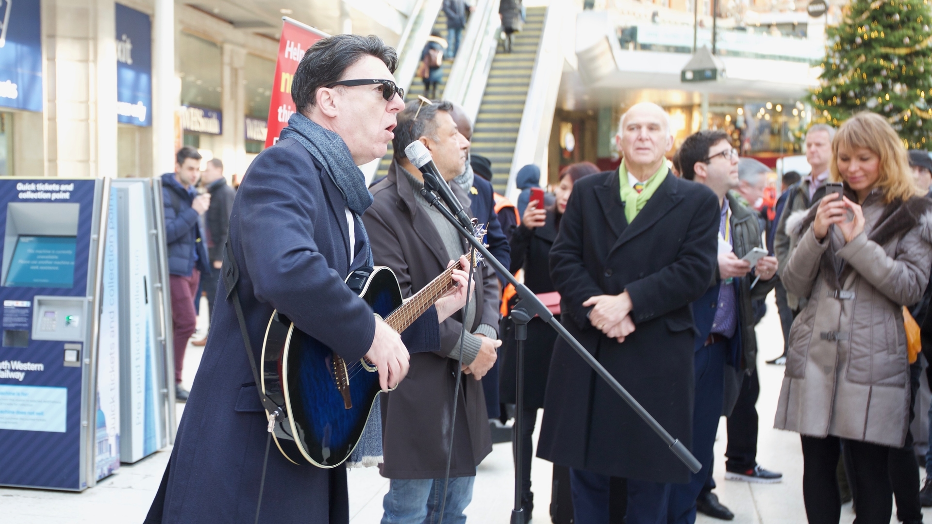 Phil Ryan sings at Waterloo Station - with Vince Cable watching