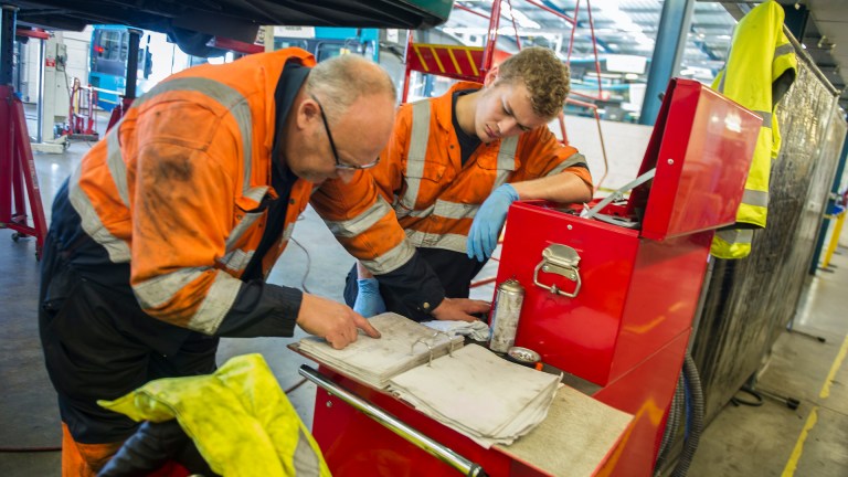 An apprentice engineer studies charts with his supervisor