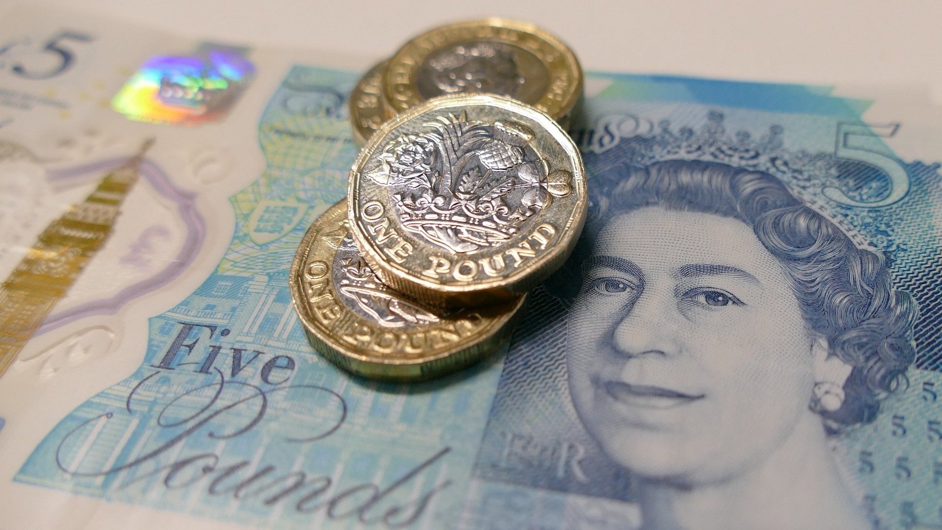 Three pound coins sit in a pile on top of a £5 note. The Big Issue explains Universal Credit