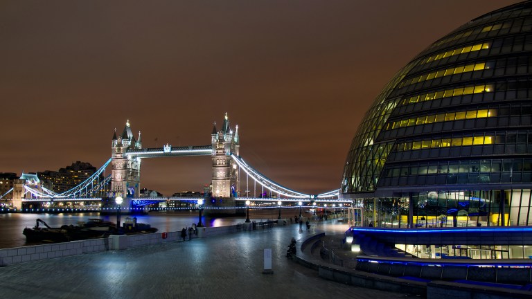 London's City Hall is lit up in the evening with Tower Bridge in the background