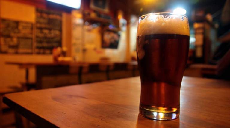 Pint of beer sits on a table in a bar