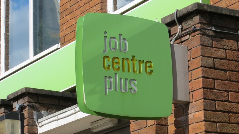 A green sign for the job centre juts out from a brick building