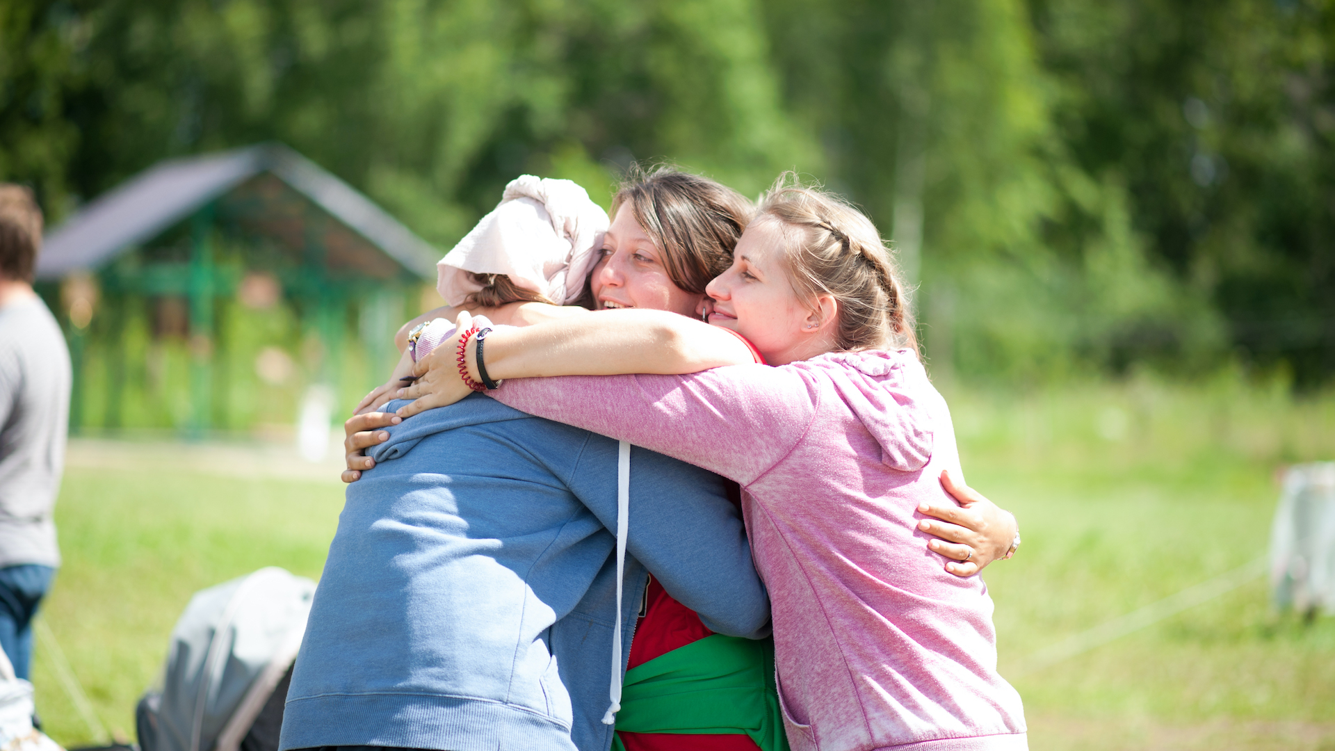 Three women hug in a field