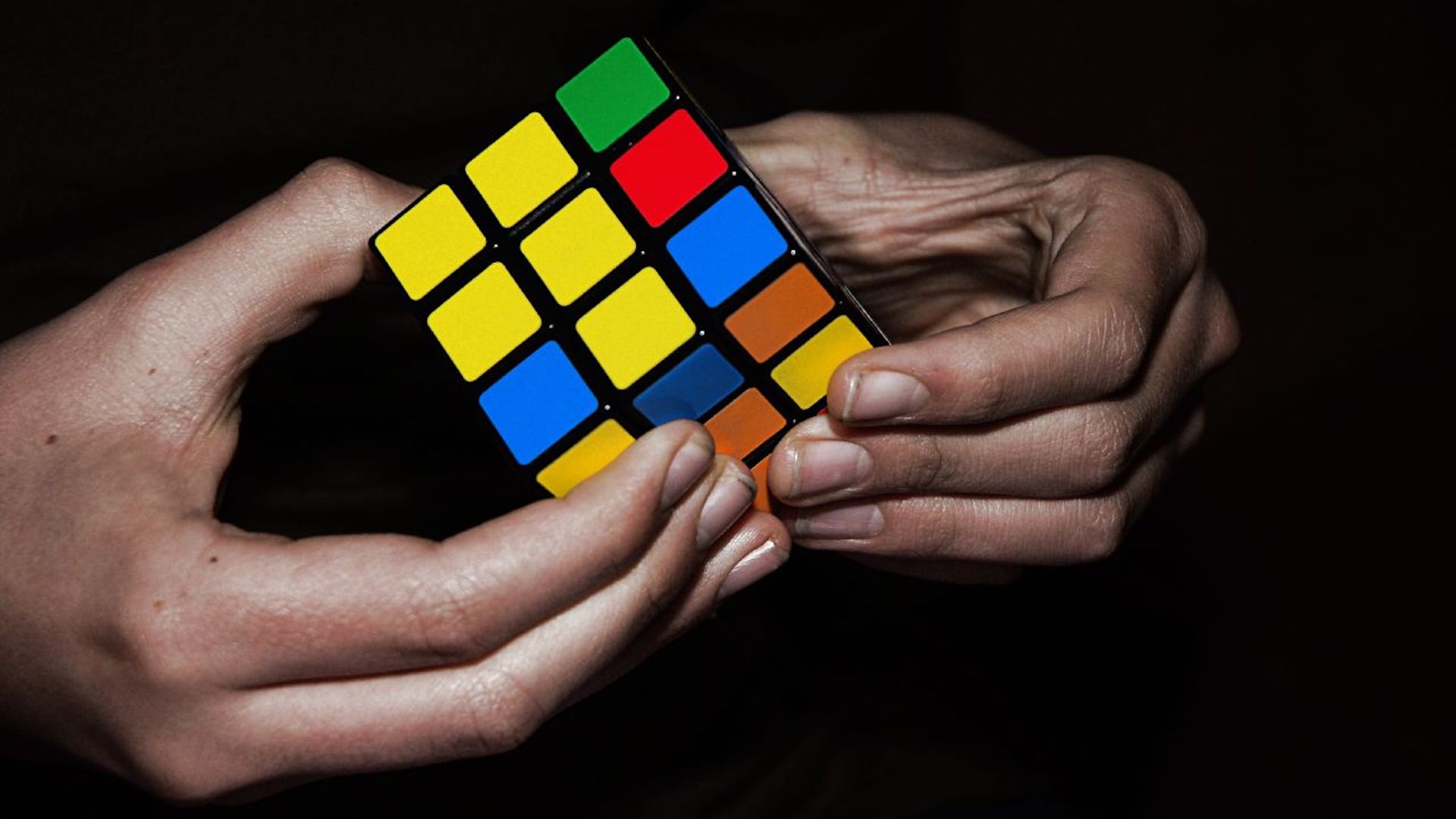 Two hands hold a Rubik's Cube