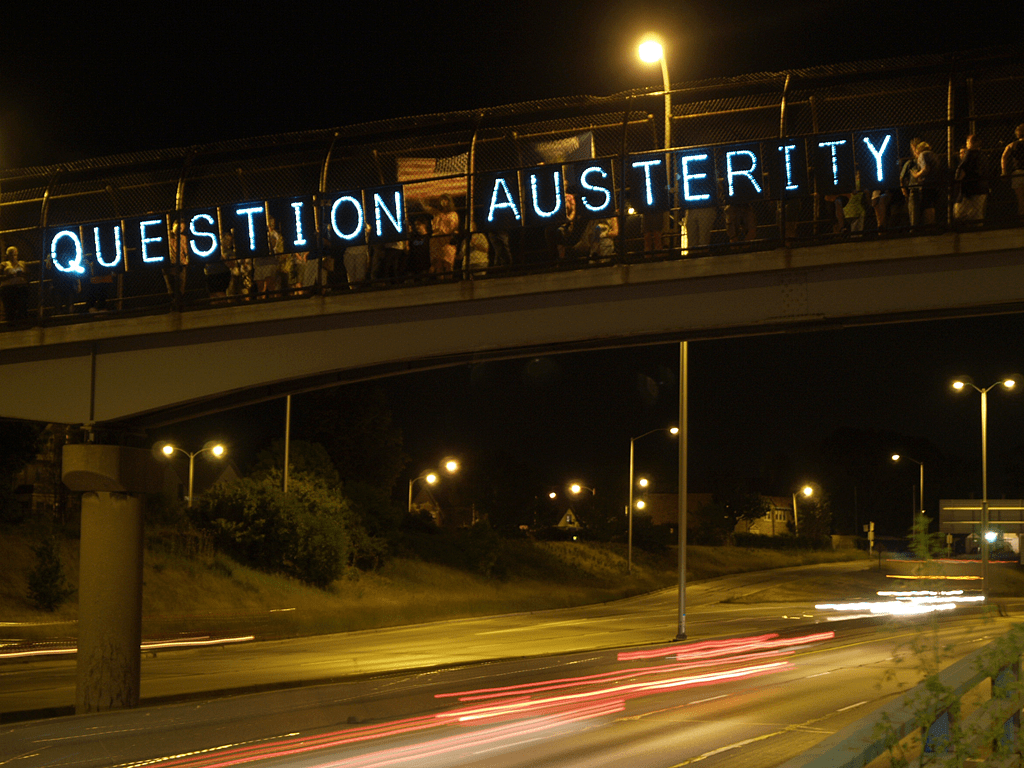 An anti-austerity message is projected onto a pedestrian overpass