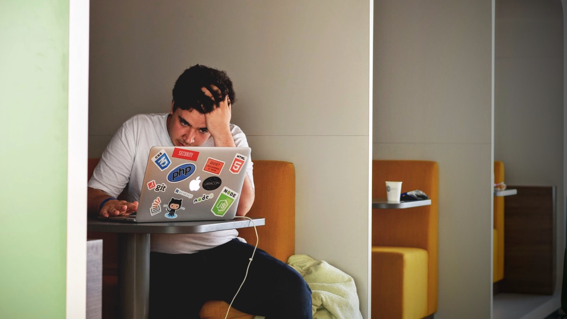 Man holds his head in his and as he looks at his computer