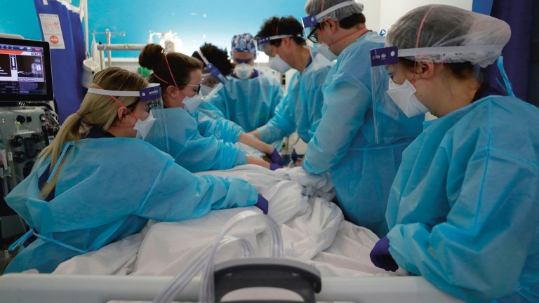 NHS workers help a patient in a hospital.