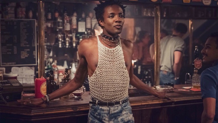 Omari Douglas stands in a bar in a string vest as Roscoe Babatunde