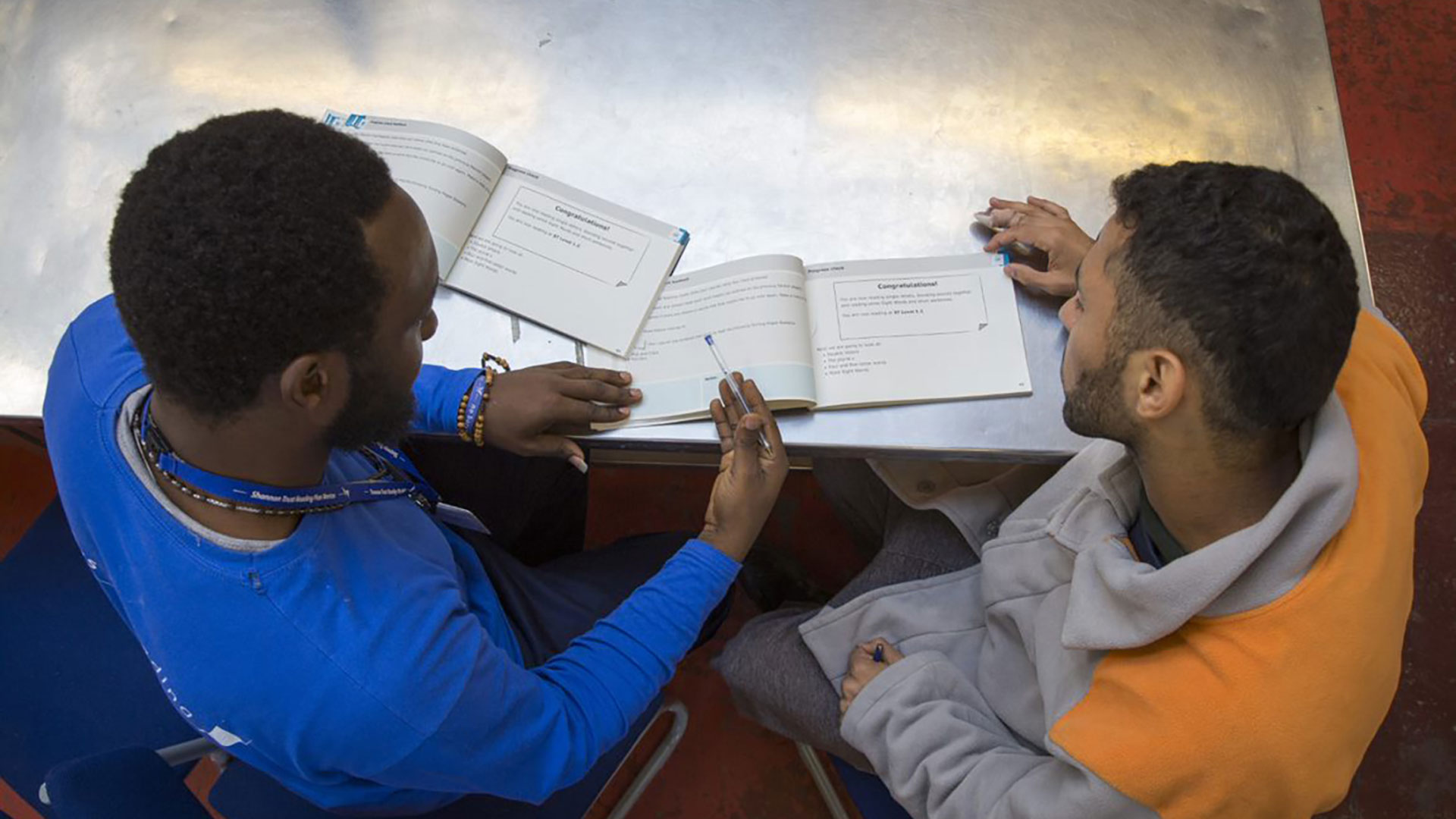 Tackling illiteracy in prison - man teaching another man to read