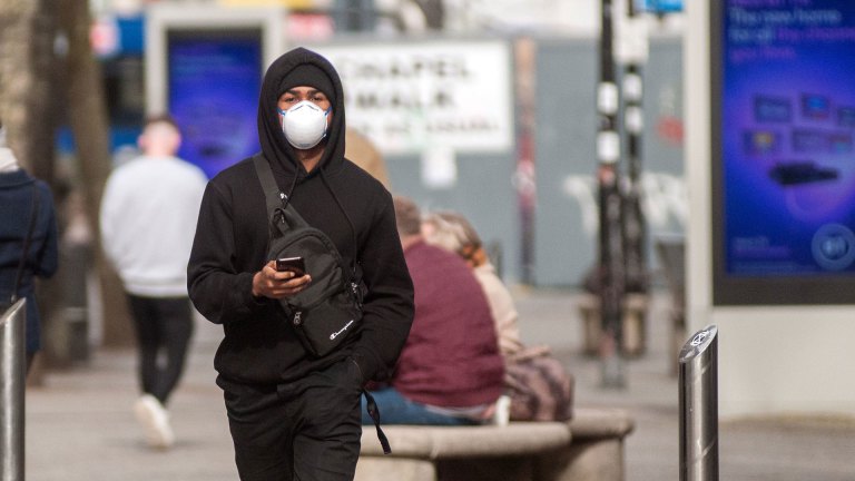 Man in mask walking down street during covid - illustrating health inequalities