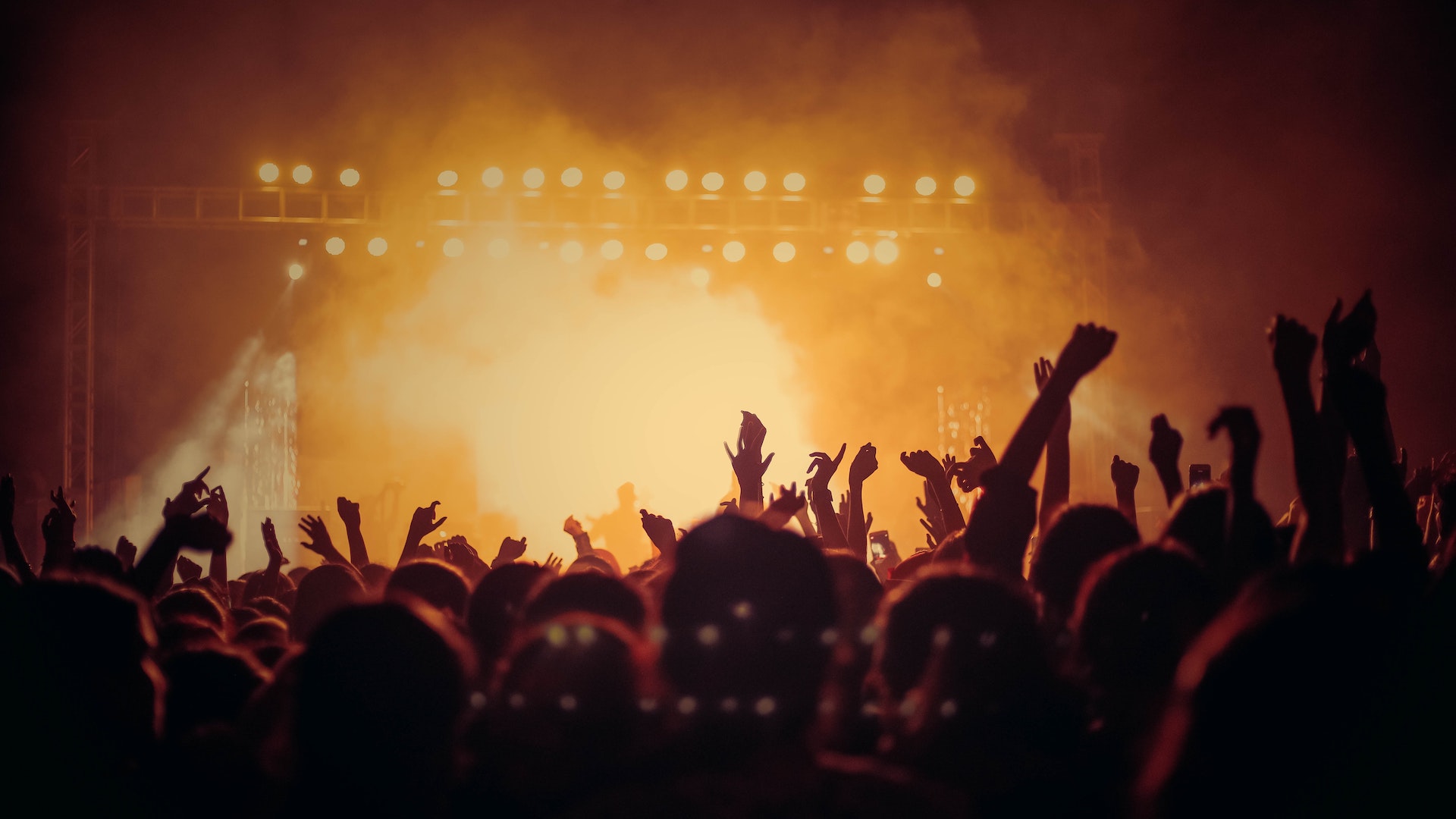 A smoky, sweaty live music venue with people's hands thrown in the air