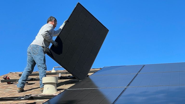 A man fits a solar panel on a roof. Up to 8,224 green jobs could be created in West Cumbria’s Copeland, where locals are objecting to controversial plans for a new coal mine