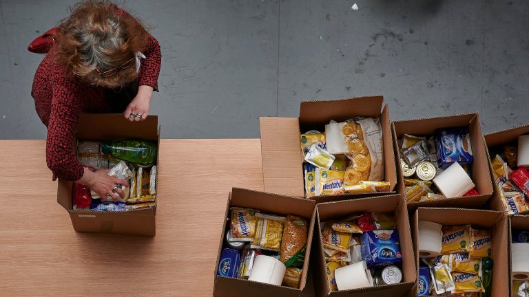 An aerial view of a woman packing food parcels at a food bank. Nearly half of people using food banks last year were in debt to the government