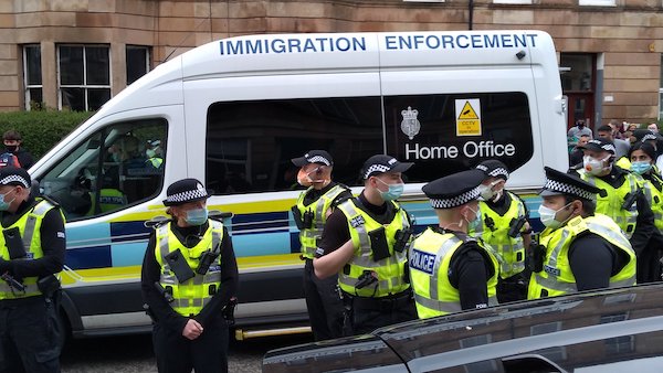 Police holding crowds back from the Home Office vehicle.