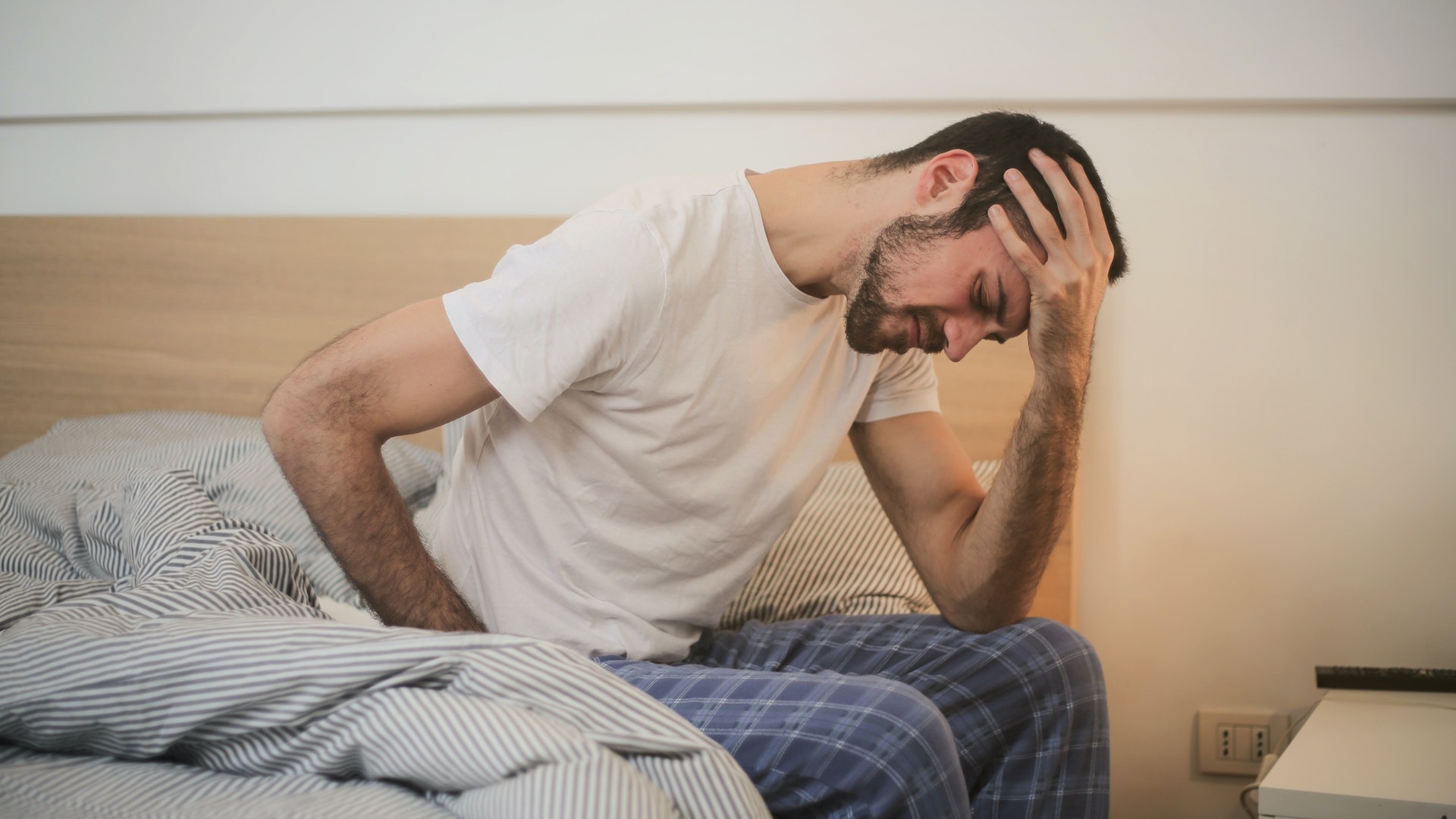 Man sitting on the edge of his bed holding his head in pain. Nearly 90 per cent of disabled people surveyed said they had little confidence the government would consider the benefits assessments changes they wanted.