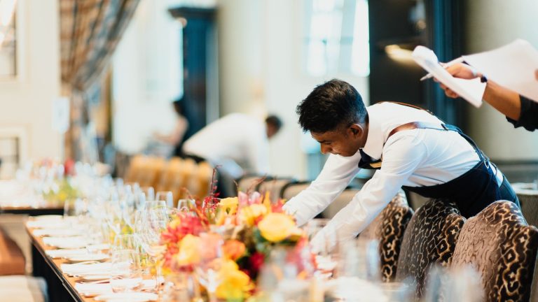 Hospitality staff lays a table for a wedding