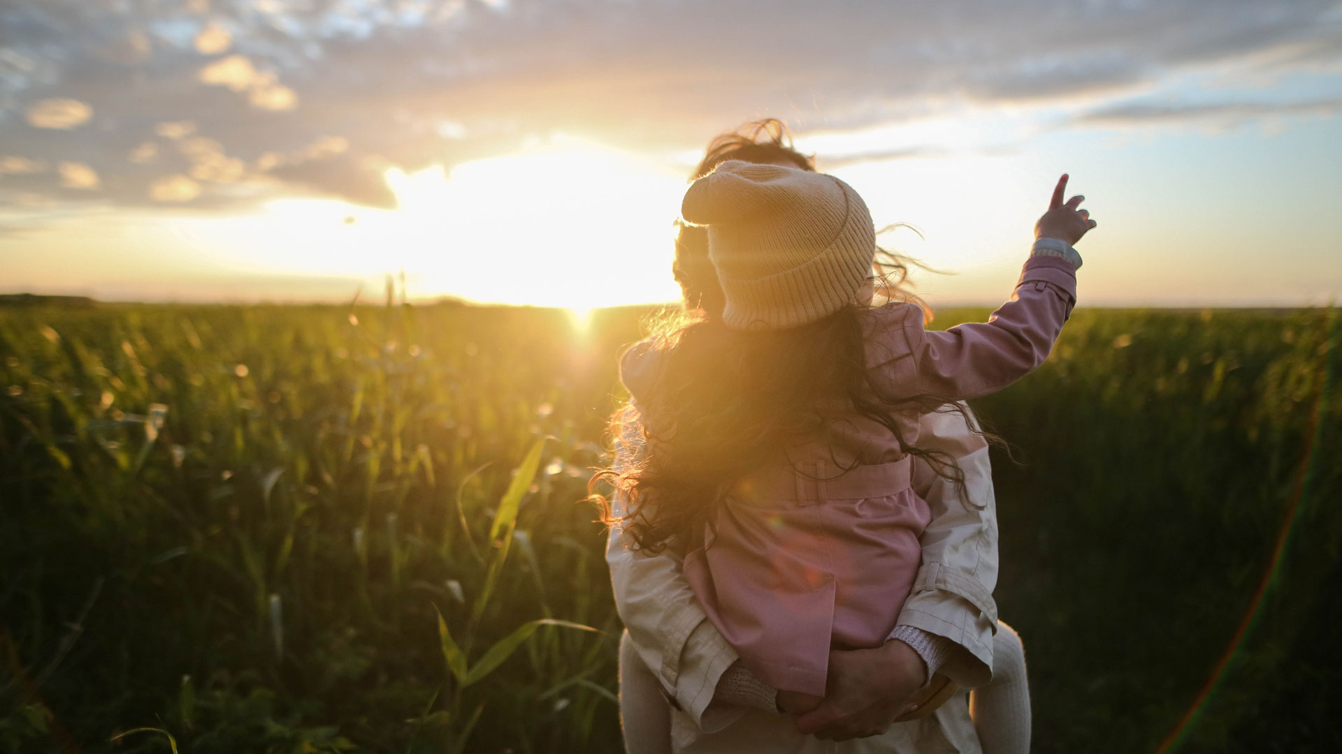 A woman and child stare into the sunset