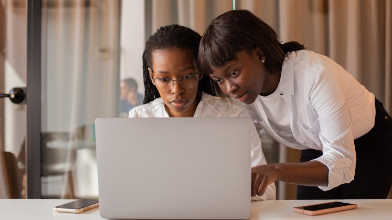 Two black women look at a laptop together
