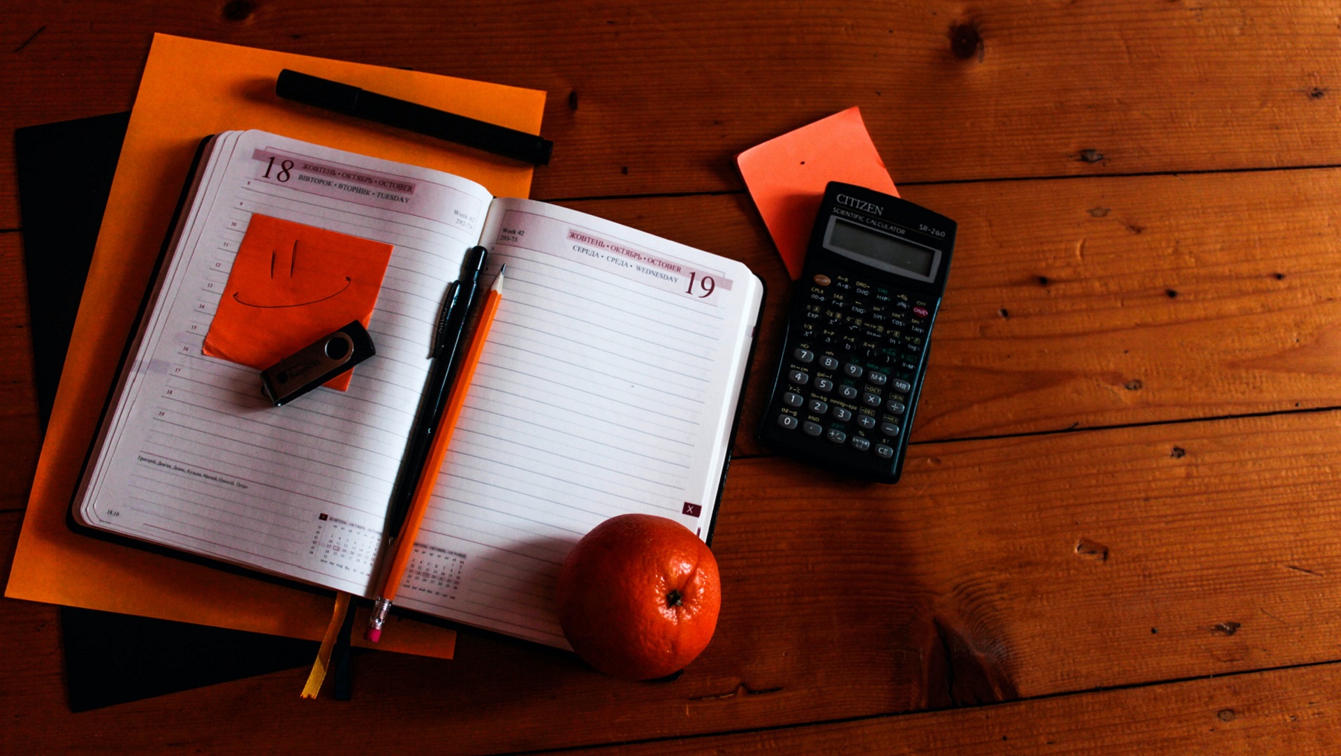 looking down on a table that has a notebook open on it alongside a pen, calculator and an apple // housing benefit