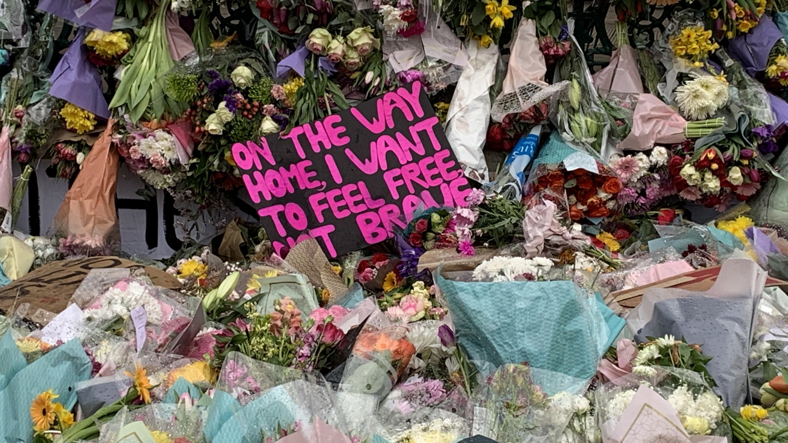 Image of flowers and placards at a vigil for Sarah Everard.