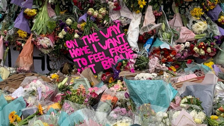 Image of flowers and placards at a vigil for Sarah Everard.