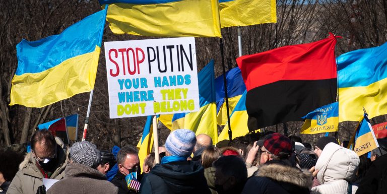 Rally against war in Ukraine with flags and sign reading 