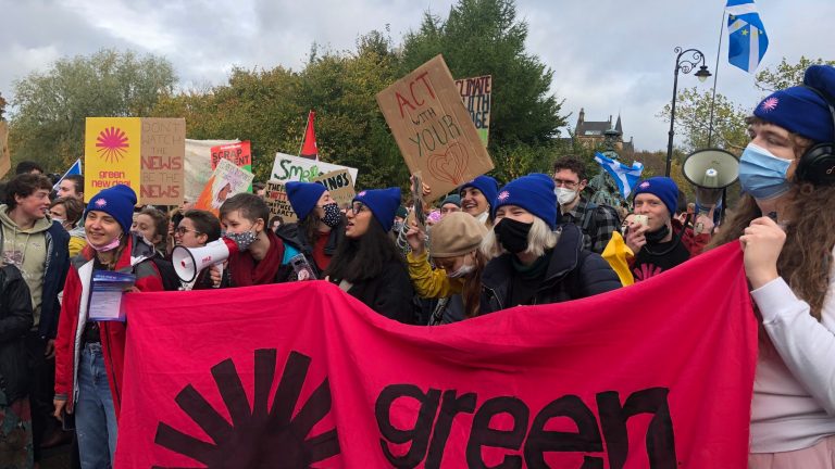 Protesters at a climate march holding a Green New Deal banner