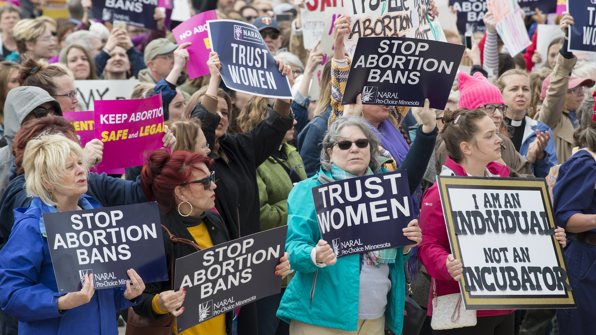 Women hold signs saying "trust women" and "i am not an incubator"