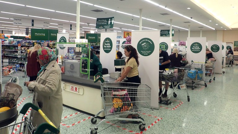 Shoppers in a supermarket stand at the check out and load their food