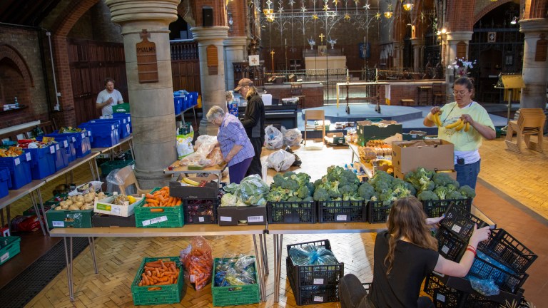 Volunteers at Earlsfield Foodbank sort food in crates in the middle of a church