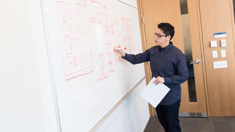 A teacher draws on a whiteboard in a school