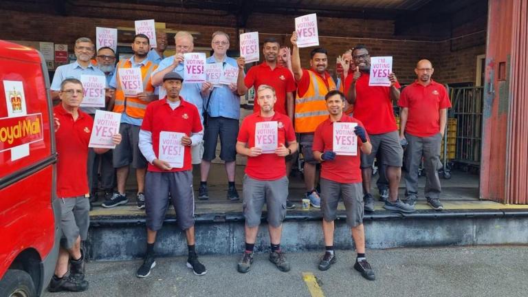 Royal Mail workers hold signs saying yes to strike action
