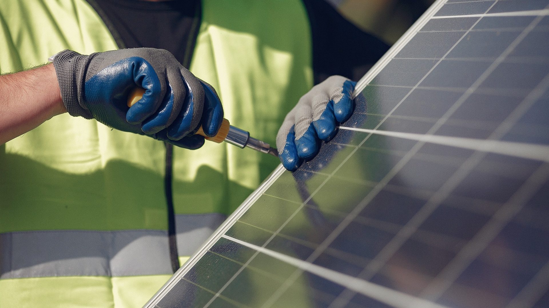 A man installs solar panels on a roof