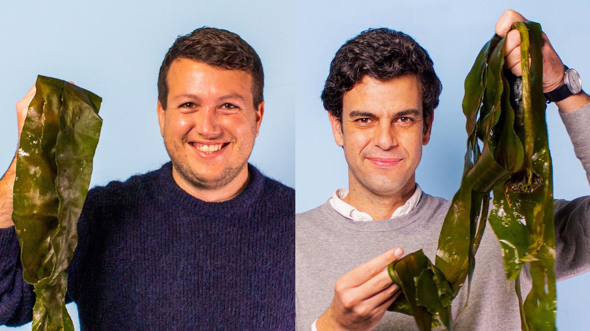 Two mean smile while holding sheets of seaweed up by their heads