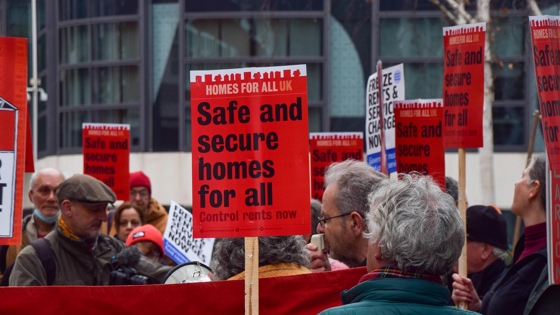 Protesters holding placards saying 'safe and secure homes for all'