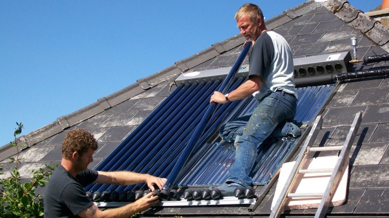 men installing solar panels on a house