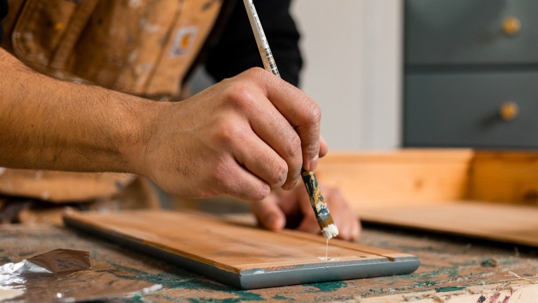 hands painting a piece of timber