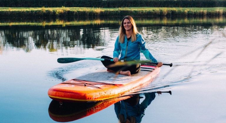 Lizzie Carr, founder of Planet Patrol, sitting on a paddle board