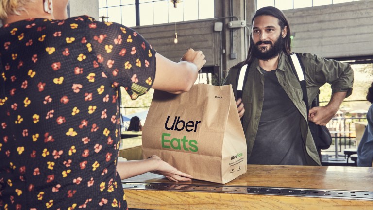 a man aproaches a restaurant counter with a paper bag saying 