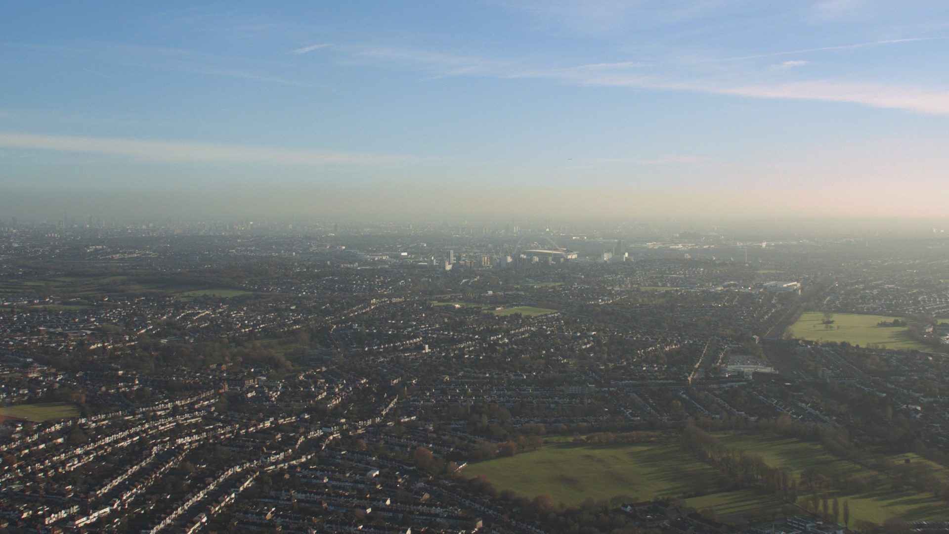 Birds-eye shot overlooking the green pastures and misty blue sky in an opening shot for the Grenfell film by Steve McQueen