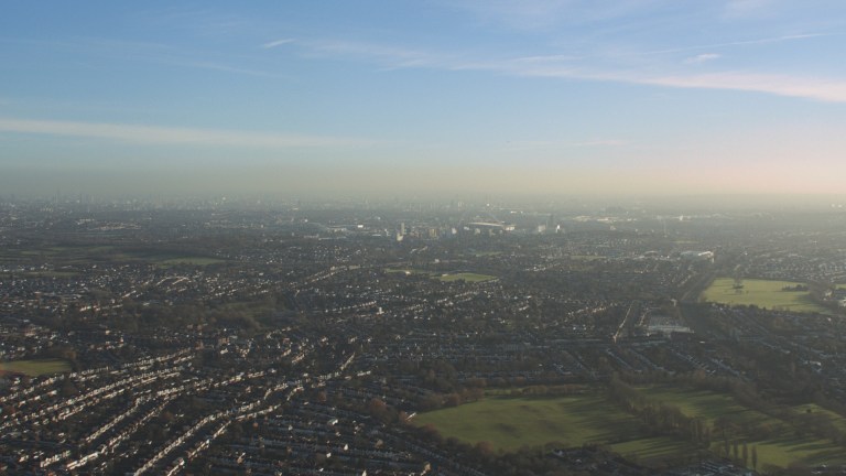 Birds-eye shot overlooking the green pastures and misty blue sky in an opening shot for the Grenfell film by Steve McQueen