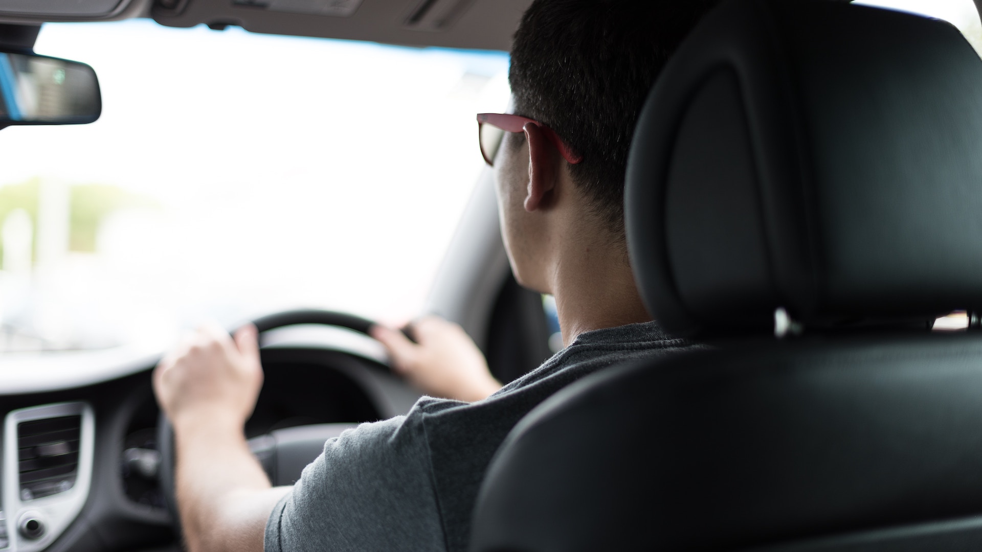 Young guy driving on the right hand side of the car to illustrate the impact of the graduate driving licences