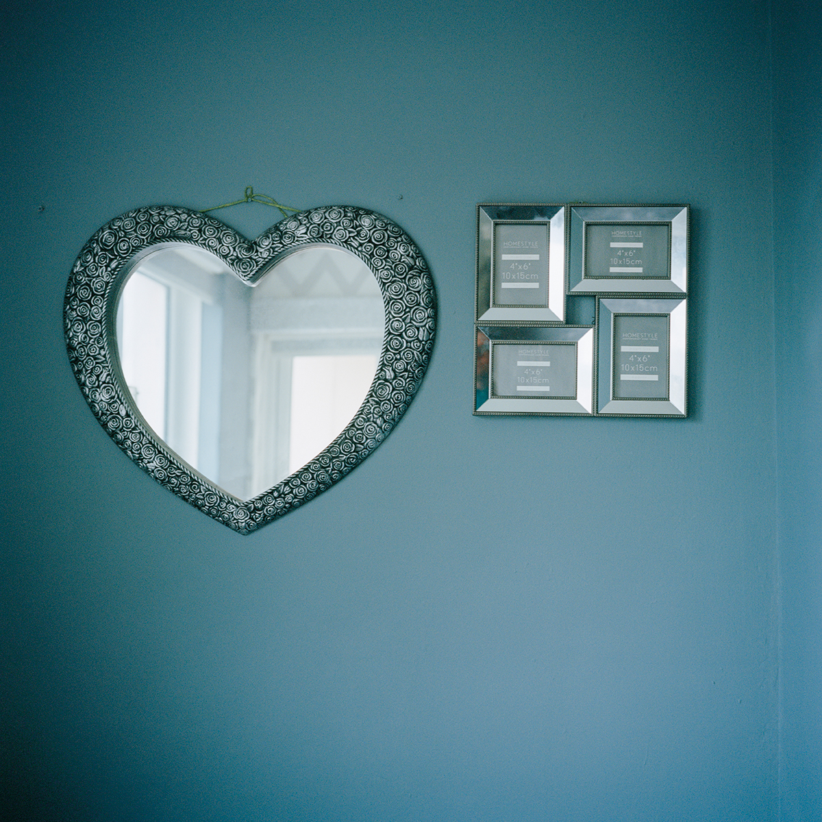 Green wall with a heart shaped mirror on it