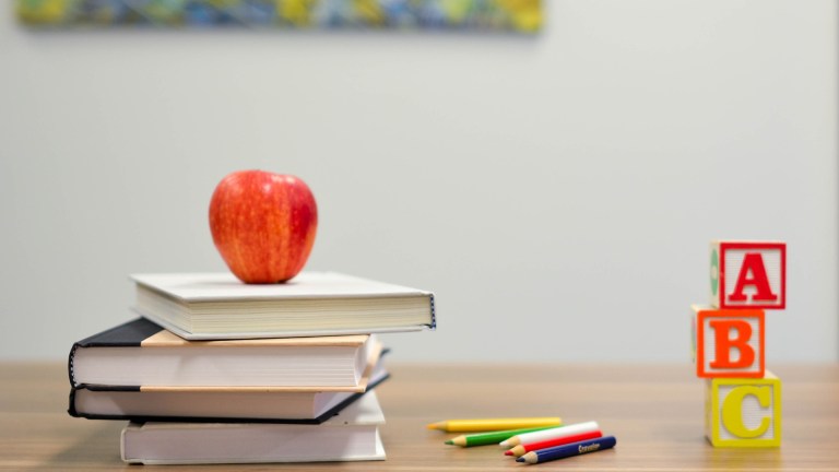 A pile of books, ABC and an apple