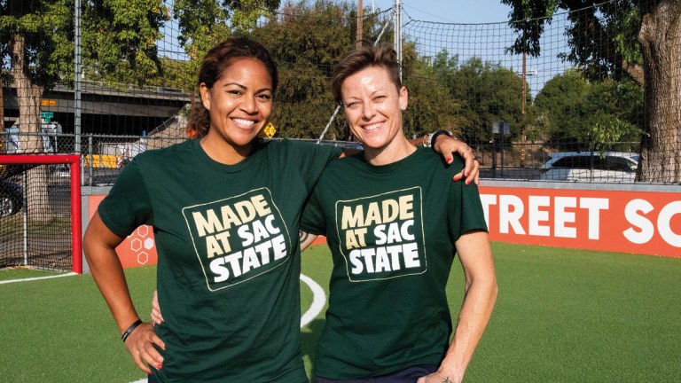 Lisa Wrightson and her team mate Tiffany Fraser stand with their arms around each other, wearing Tshirts saying 'made at Sac state'