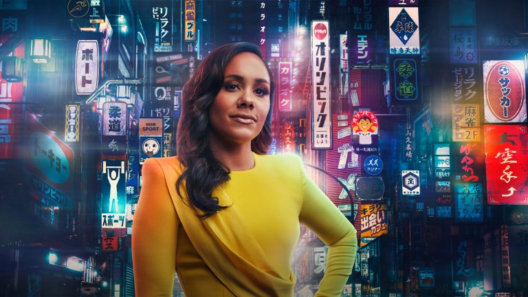 Alex Scott wearing yellow in front of Japanese neon signs
