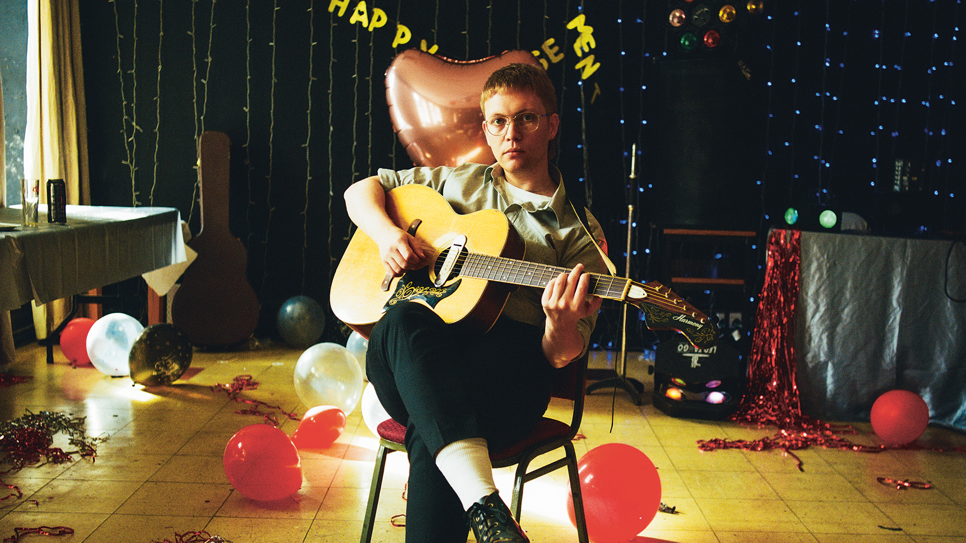 The Howl & The Hum's Sam Griffiths sitting on a chair playing guitar