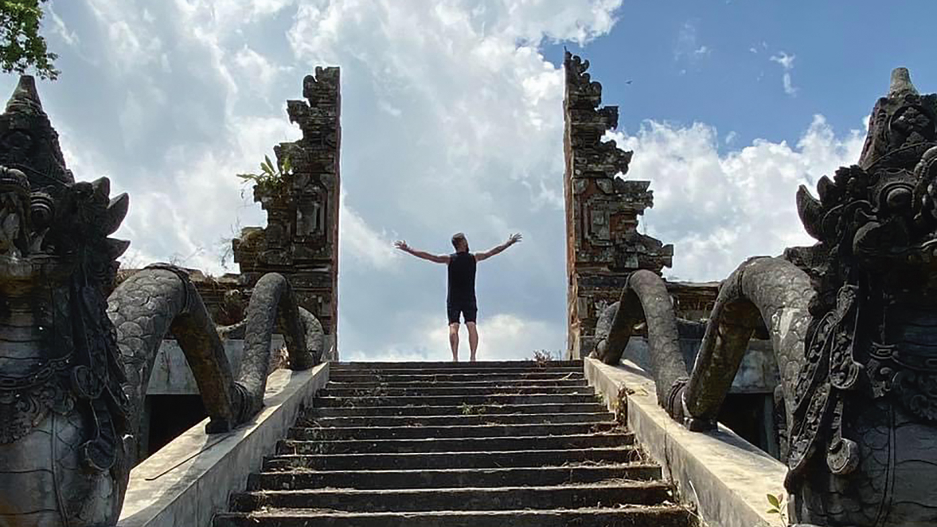 The Bearded Explorer at the top of some stairs with arms raised