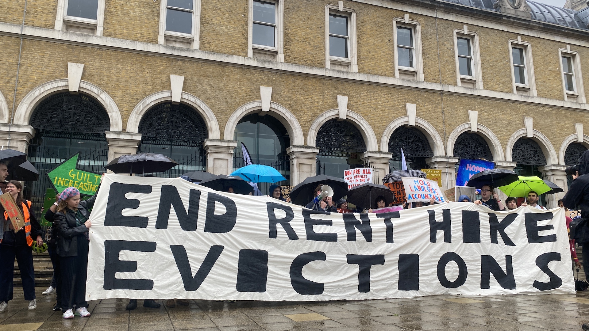 Protesters hold a banner which reads "end rent hike evictions"